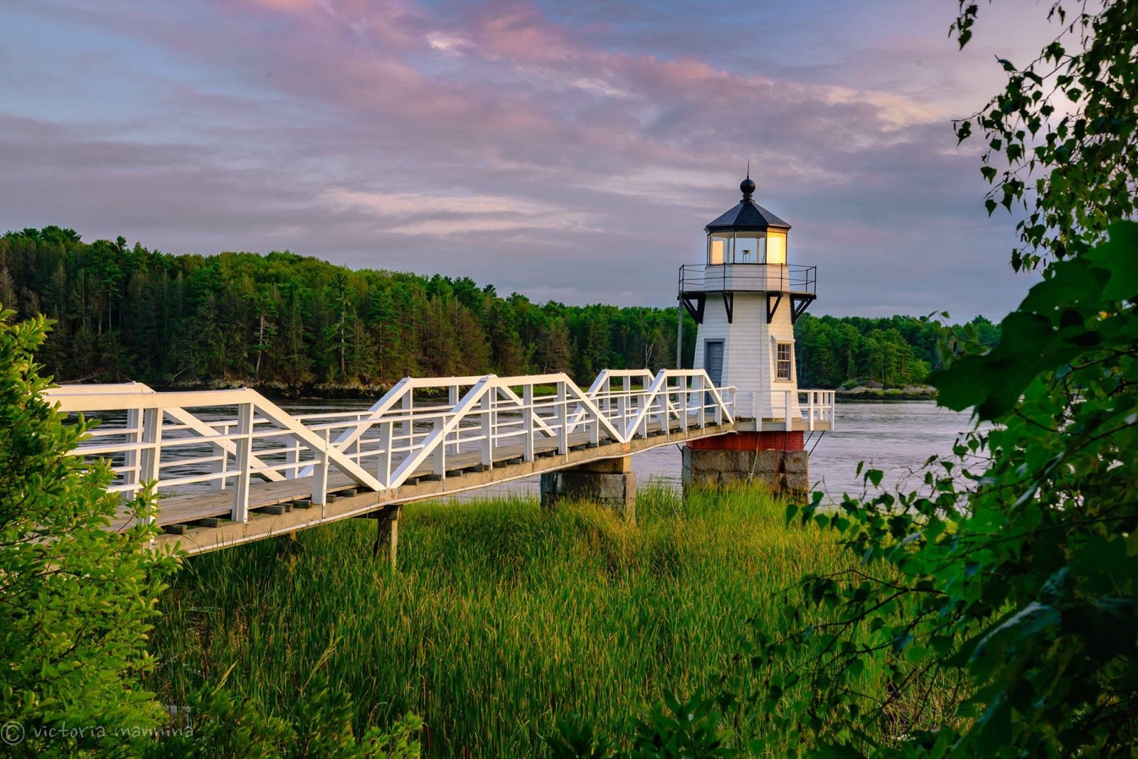 Illuminated lighthouse at end of a walkway, twilight sky
